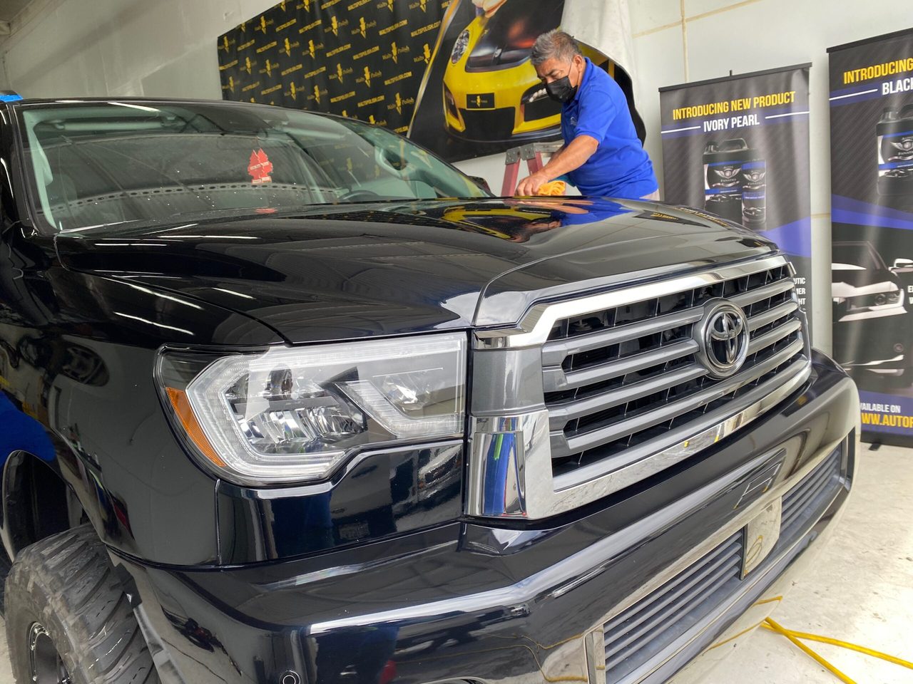 A black Toyota SUV being hand-detailed to a deep gloss finish