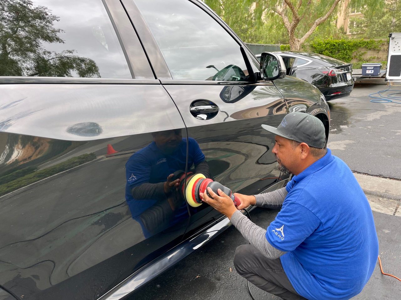 A detailer machine-polishing the side panel of a car to remove swirl marks